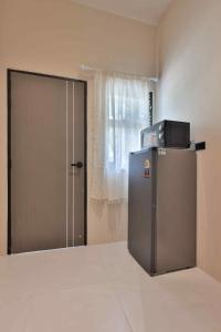 a room with a refrigerator and a door with a window at De Helga Apartment Chaloklum in Ko Phangan