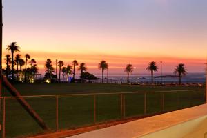 a sunset over a field with palm trees at Camps Bay Beach Apartment in Cape Town