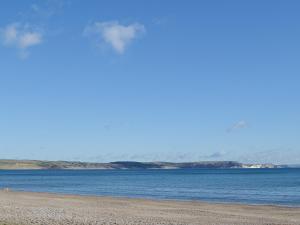 einen Strand mit Wasser und Bergen im Hintergrund in der Unterkunft Rose Cottage in Winterborne Steepleton