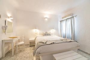 a white bedroom with a bed and a desk at Artemis Suites in Megalochori