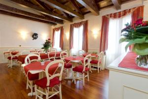ein Esszimmer mit roten Tischen, Stühlen und Fenstern in der Unterkunft Ca' San Polo in Venedig