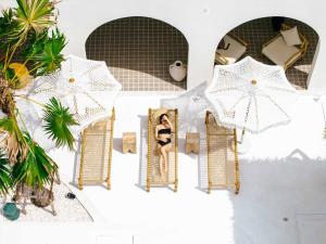 a woman in a bikini in a mirror in front of umbrellas at Ginevra Khaolak in Khao Lak