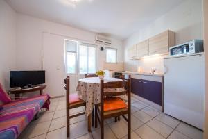 een kleine keuken met een tafel en een koelkast bij Garden Apartments in Komiža