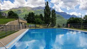 a large blue swimming pool with mountains in the background at Apartamento Argualas V - WOWRURAL in Panticosa