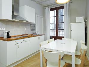 une cuisine avec des placards blancs et une table et des chaises blanches dans l'établissement Barcelona Mercaders Apartments, à Barcelone 26 autres photos