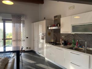 a kitchen with white cabinets and a table and a couch at Happy House Montemarciano in Montemarciano