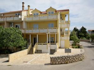 a large yellow house with a stone wall at Apartments Jasmina in Novalja