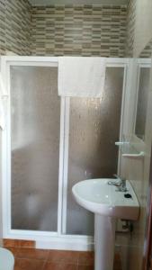 a bathroom with a sink and a glass shower at Hostal las Parcelas in Conil de la Frontera