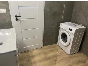 a washing machine in a bathroom next to a door at Apartmán Bobrov 2 in Bobrów