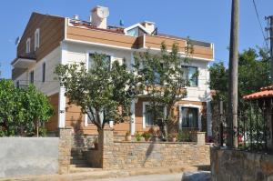 a house with a tree in front of it at Suna Apart Hotel in Gokceada Town