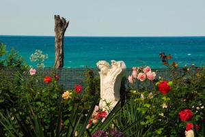 a statue in a garden with flowers and the ocean at La Casa Primorsko in Primorsko