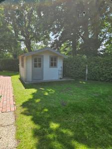 a small house in a grassy yard with trees at Ferienhaus mit großem Garten in Friedeburg