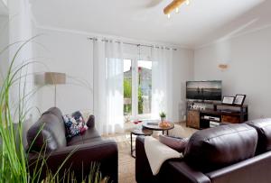 a living room with two leather couches and a tv at Haus Duene in Ostseebad Karlshagen
