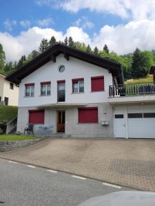 a white house with red doors and a balcony at Appartamento Vacanza 2 locali in Quinto