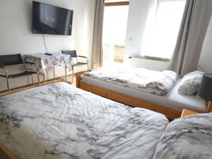 a bedroom with two beds and a tv on the wall at Unterkunft für Monteure in Schwallungen