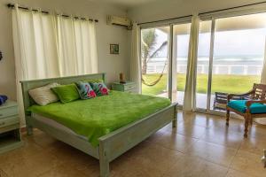 PalenqueにあるCaribbean Paradise Beachfront Villaのベッドルーム1室(緑のシーツが敷かれたベッド1台、窓付) +6枚の写真