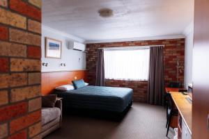 a hotel room with a bed and a brick wall at Scone Motor Inn & Apartments in Scone +82 photos