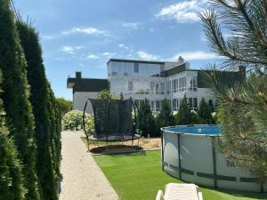 a large white building with a swimming pool in a yard at Гостевой дом SUN TAG in Chornomors'ke