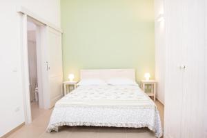 een witte slaapkamer met een wit bed en 2 tafels bij Nonna Nina in Guagnano