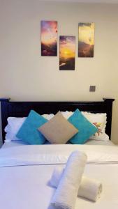 a white bed with pillows and pictures on the wall at Sure Stay Homes in Gatunga