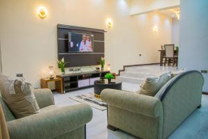a living room with two chairs and a flat screen tv at Lakeluxhomes Apartment in Ibadan