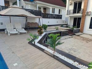 a patio with an umbrella and chairs and a pool at Serene BnB - Apt 04 Makongo after Mlimani City in Dar es Salaam