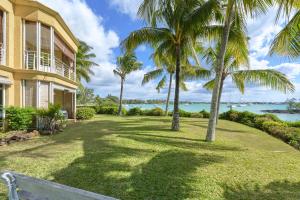 a house with palm trees in front of a yard at Ilot Bleu, beachfront flat, centre of Grand Baie in Grand Baie