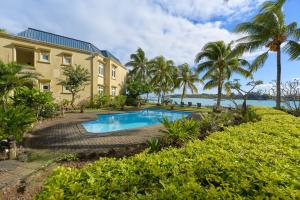 a house with a swimming pool and palm trees at Ilot Bleu, beachfront flat, centre of Grand Baie in Grand Baie