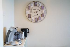 Un reloj colgado en la pared encima de una cafetera. en Azuréa, vue mer avec ses 2 piscines, en Cannes