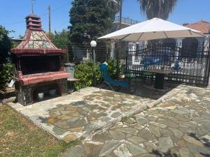 a fireplace with a table and an umbrella in a yard at Erifyli in Nea Kallikrateia