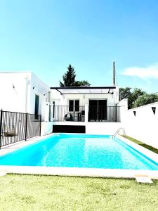 a swimming pool in front of a white house at Le Cabanon Meublé de Tourisme trois étoiles in Entraigues-sur-la-Sorgue