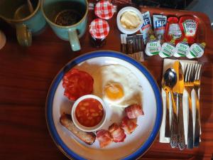 a plate of breakfast food with an egg and bacon at The Lodge Stanwell in Stanwell
