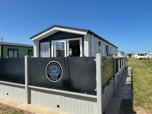 a house behind a fence with a gate at Sunnymede B5 - Fantasy Island - HOT TUB, ramped decking, patio doors, central heating, pet friendly - Meadow Lakes Caravan & Lodge Hire in Ingoldmells