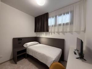 una piccola camera con letto e televisore di Suites Marilia Apartments Pool Side - Suite Livorno Holiday Home Group a Livorno