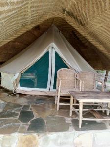 a tent with two chairs and a wooden table at cyuza paradise island in Nyarugina