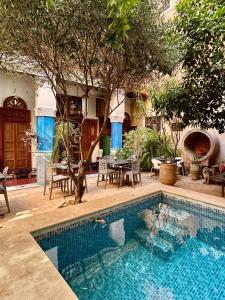 a swimming pool in a yard with a table and chairs at Les Bains de Fez Tara in Fès