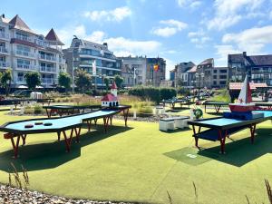 um grupo de mesas de pingue-pongue em um parque com prédios em Appartement Ann em Blankenberge