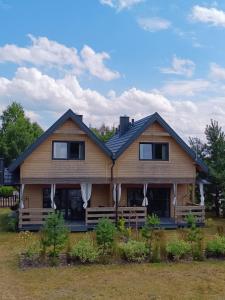 una gran casa de madera con techo negro en Szumiące Drzewa, en Debina