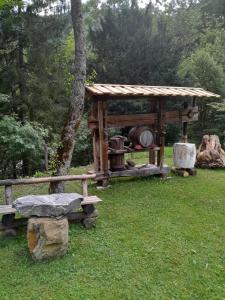 a wooden gazebo and a bench in the grass at Hiša pod Rogatcem - studio in Luče