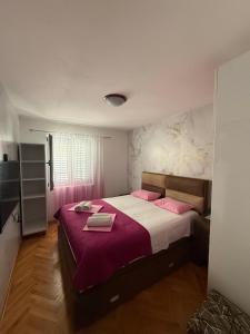 a bedroom with a large bed with pink pillows at Apartment Stana in Petrovac na Moru