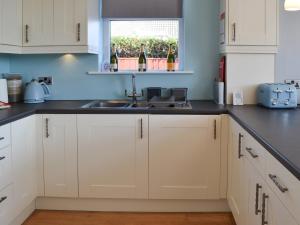 a kitchen with white cabinets and a sink and a window at Grays Cottage in Sewerby +15 photos