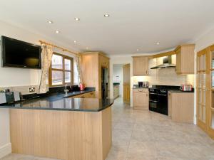a large kitchen with wooden cabinets and a black counter top at Magnolia Cottage in Aberaeron