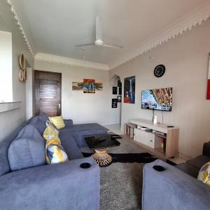 a living room with two blue couches and a tv at HawiHomes in Mombasa