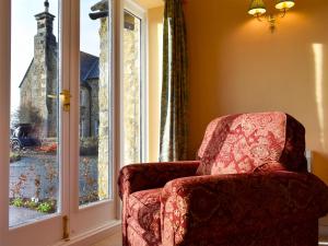 a red chair sitting in front of a window at Grange Cottage in Winston