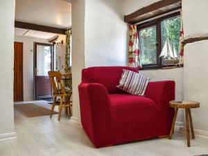 a red chair in a living room with a window at Tarow Cottage in East Looe