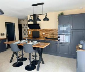 a kitchen with gray cabinets and a wooden table and chairs at Les clés de jade in Cavignac