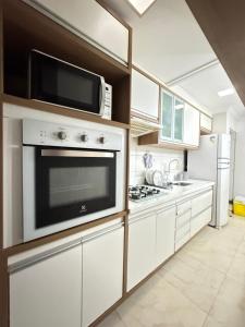 a kitchen with white cabinets and a microwave at Residencial MW Novo in Camaçari