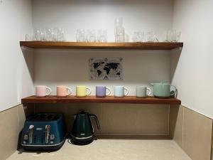 a shelf with mugs and glasses on it with a kettle at The Crossing Retreat in Turangi
