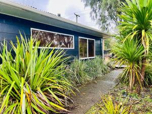 a blue house with palm trees in front of it at The Crossing Retreat in Turangi