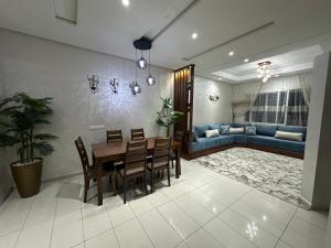 a dining room and living room with a table and chairs at SunRose appartement, Luxueux, sécurisée, piscine, Wi-FI, Pool et parking in El Jadida